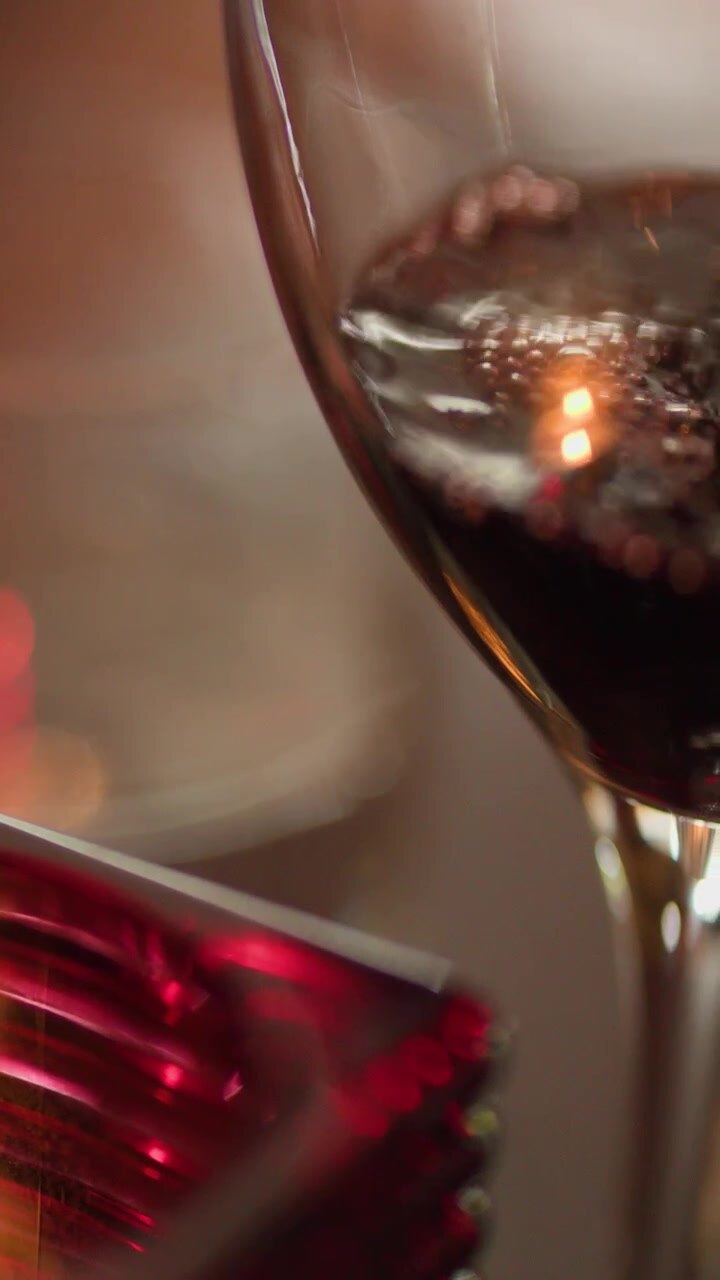 Close-up de vinho tinto sendo derramado em uma taça, ambiente acolhedor de restaurante à luz de velas, profundidade de campo rasa.