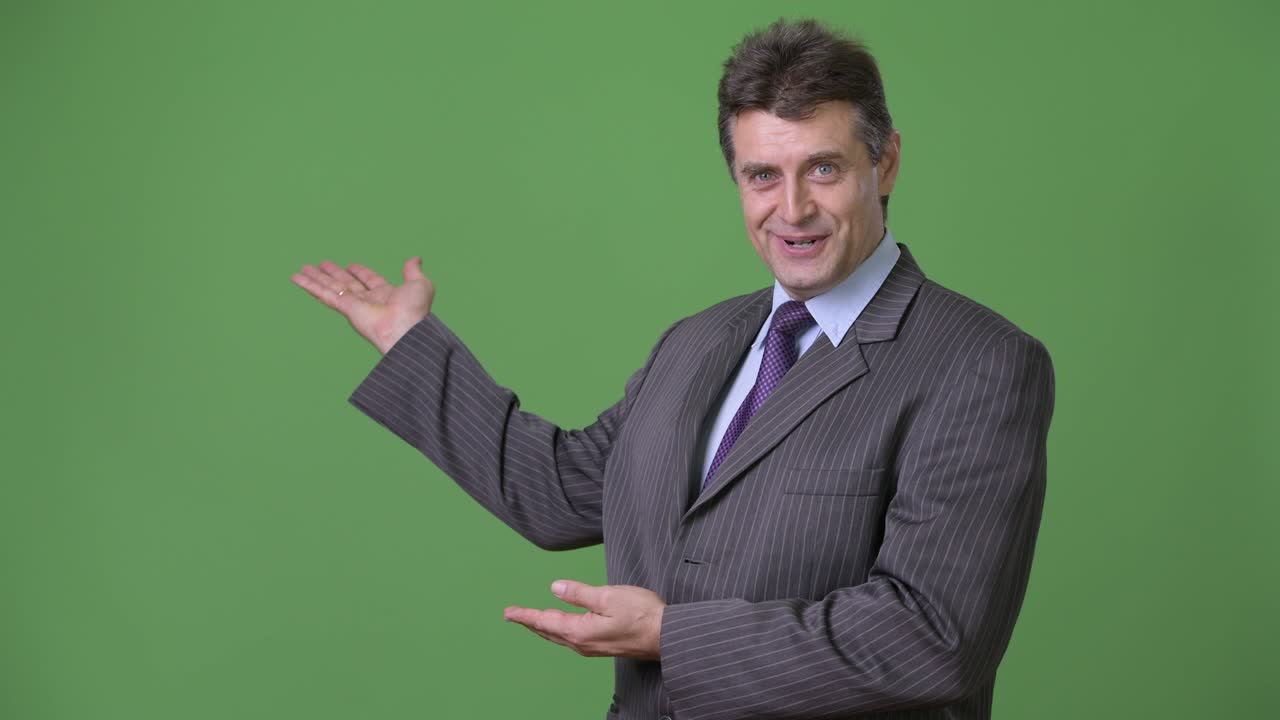 hombre de negocios maduro y guapo contra un fondo verde