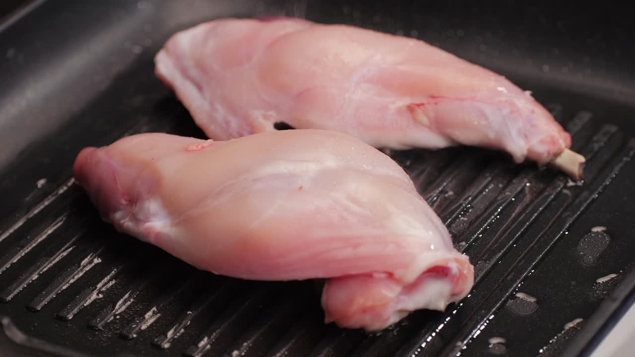 Roasted rabbit legs in a grill pan, healthy diet meat close up, chef cooking rabbit on kitchen restaurant, Black background. Top view