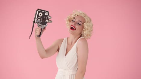 woman in 1940s/50s style dress holding a movie camera