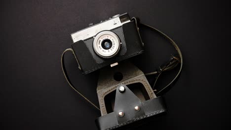 old retro film camera in leather case on black background