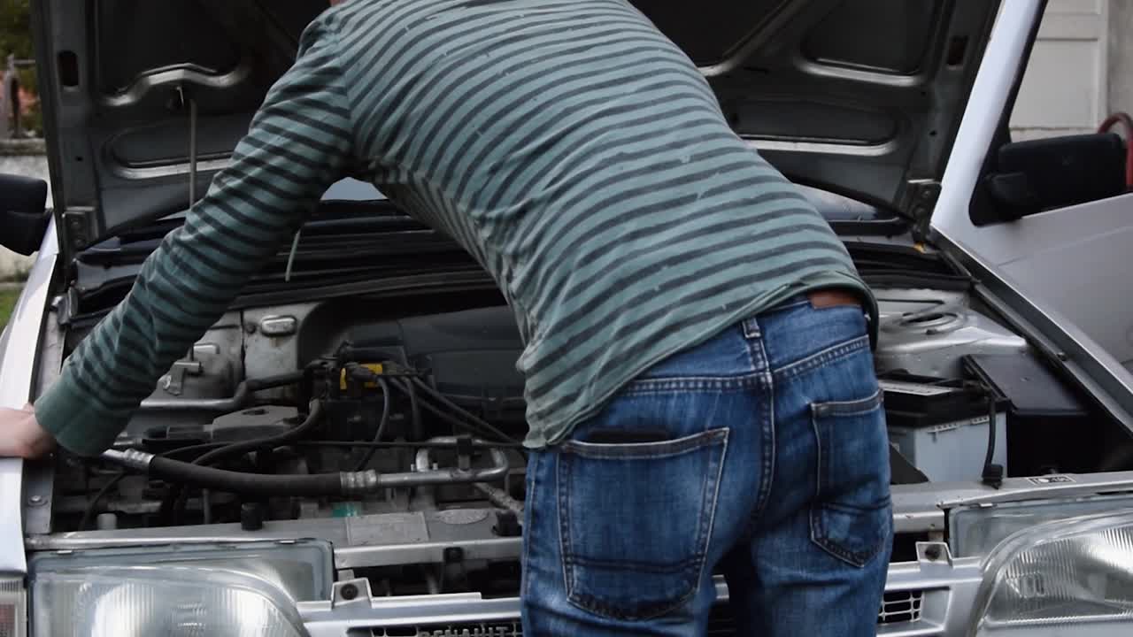 Young man works on repairing an old broken down car engine