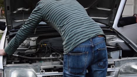 un joven trabaja en la reparación de un viejo motor de coche averiado.