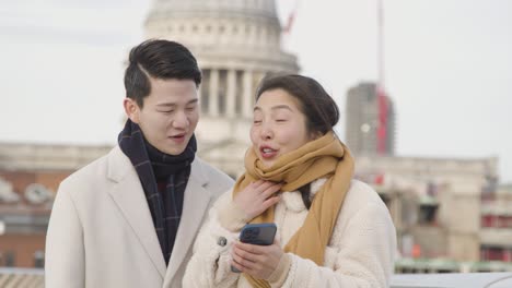 백그라운드에서 세인트 폴 대성당과 밀레니엄 다리를 건너 휴일에 젊은 아시아 부부