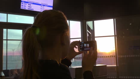 mujer tomando fotos del atardecer con el celular