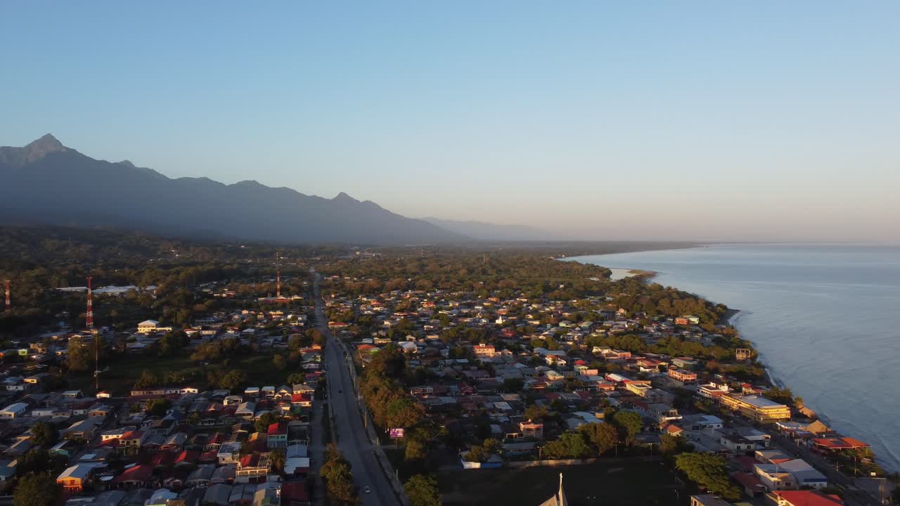 vista aérea de una ciudad costera al amanecer, mostrando la extensa costa y las casas bañadas en la luz de la madrugada