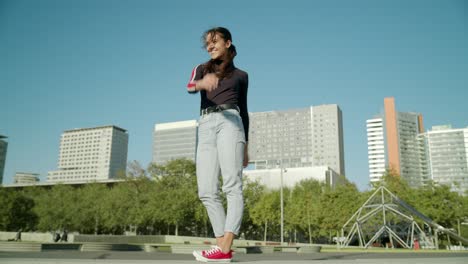 Empowered-Happy-Young-Attractive-Latin-Woman-does-an-energetic-jump-looking-towards-the-sun-on-a-sunny-day-at-the-Barcelona-forum-city-wide-angle-shot