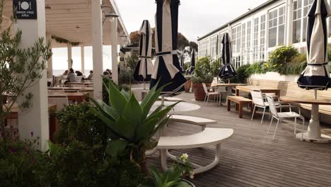 waiter walking through outdoor restaurant with plants and tables