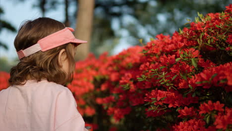 Cute-young-toddler-looking-at-red-azaleas-with-magnifying-glass