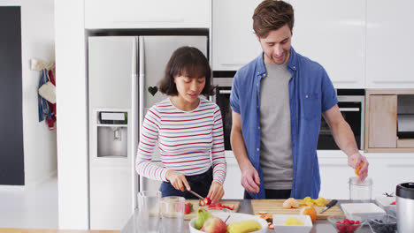 Video-of-happy-diverse-couple-preparing-meal-together-in-kitchen