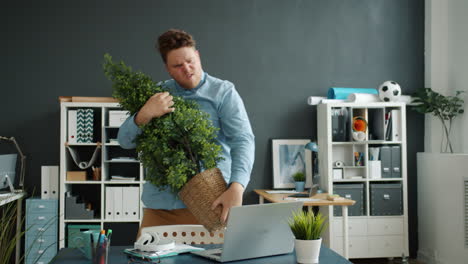 man struggling with a plant in the office