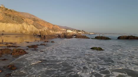 beautiful view of waves rolling from the pacific ocean into the shore at el matador beach during golden hour, malibu california