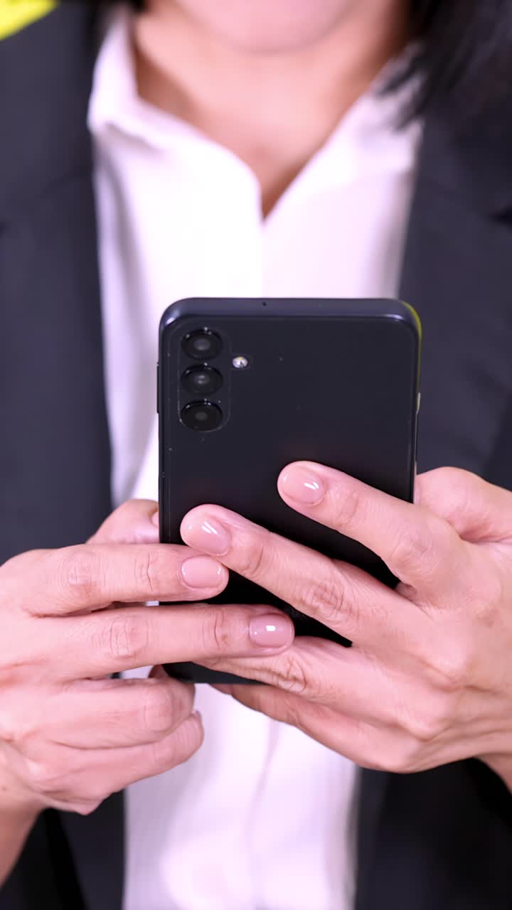 Primo piano delle mani di una donna d'affari che digitano su uno smartphone, telecamera fissa, illuminazione da studio luminosa, inquadratura verticale