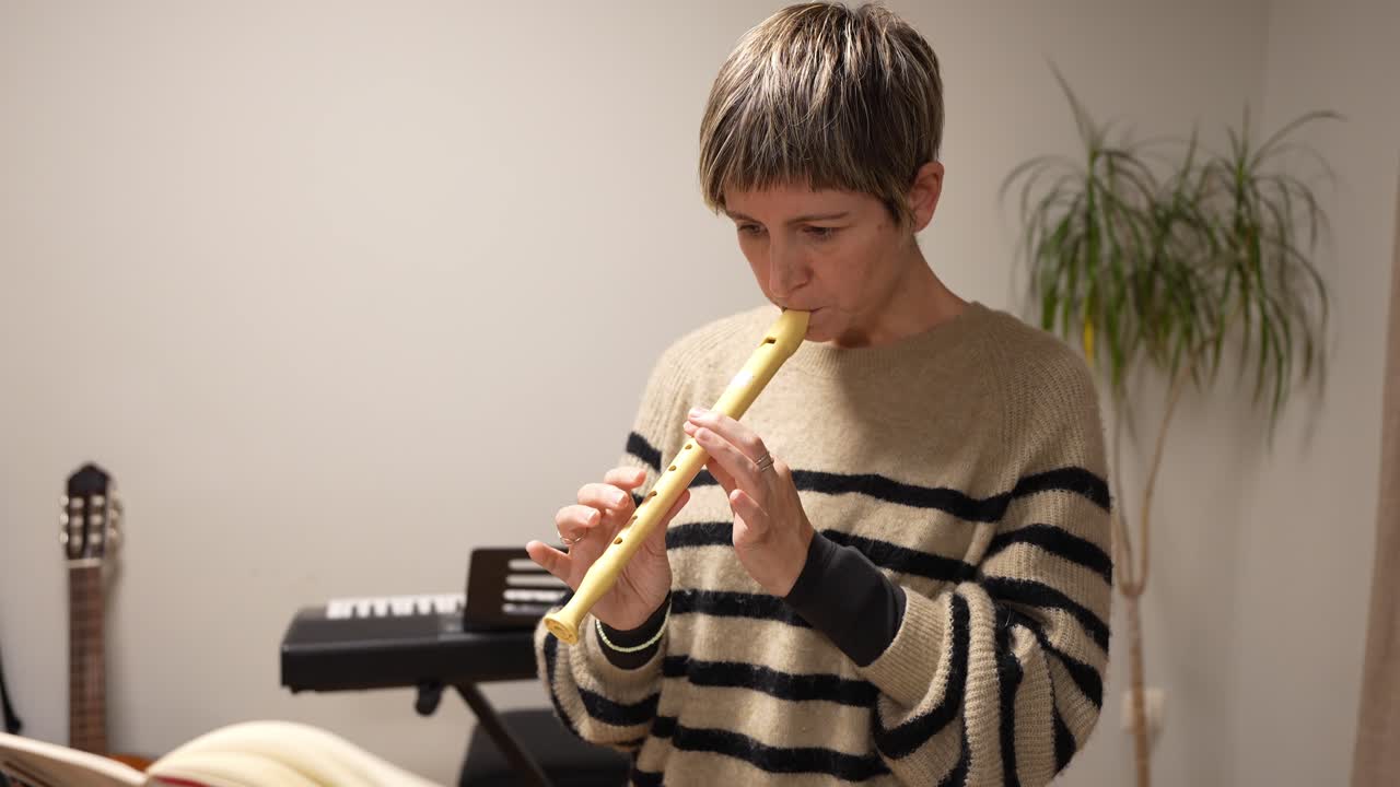 Donna che suona il flauto dolce e legge uno spartito musicale al chiuso