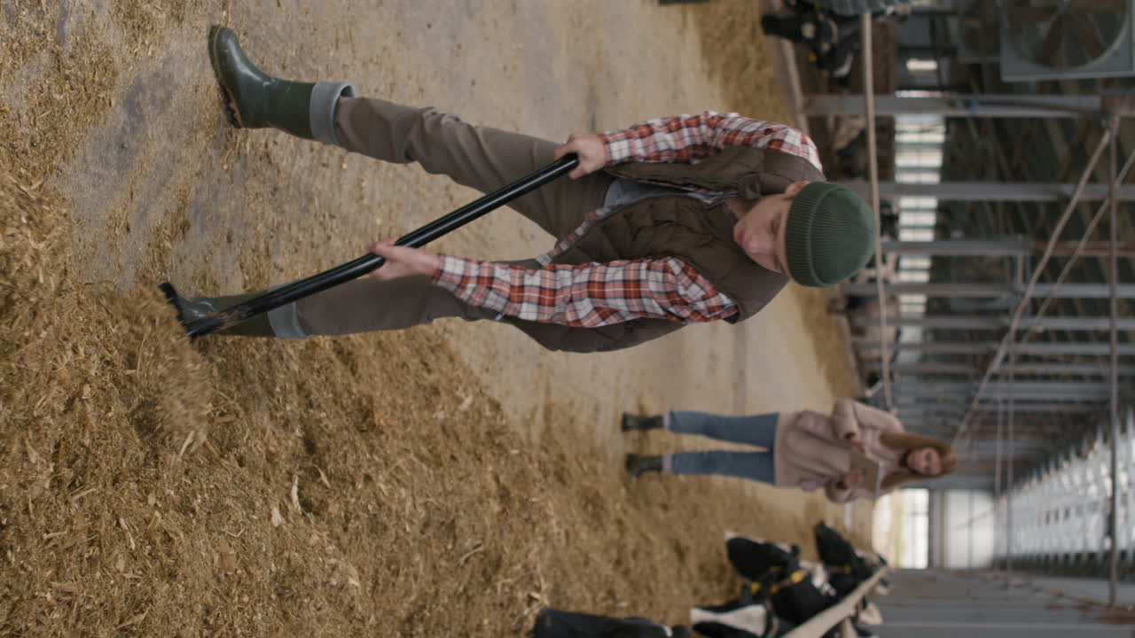 Vertical Shot of Teenage Boy Shoveling Hay at Farm