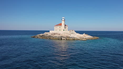 aerial view of mulo lighthouse on small island in croatian adriatic sea water on sunny summer day, drone shot