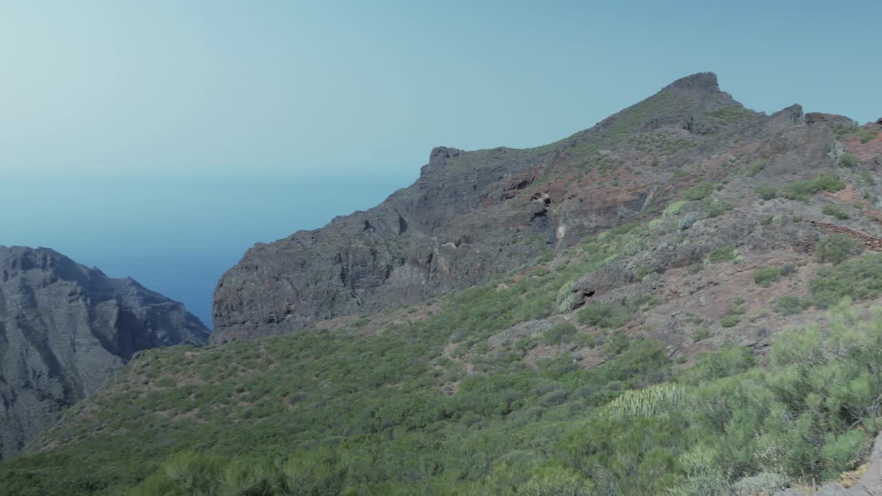 테네리페의 테노 산맥에서 여성 하이커와 함께 바다와 바위 길로 내려가는 높은 곳의 풍경