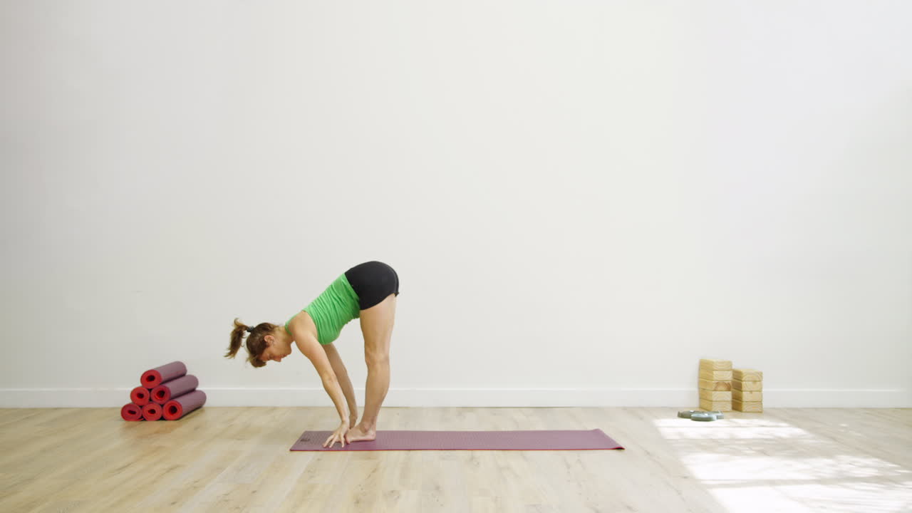 Mulher praticando yoga na postura da pinça em um tapete, em estúdio.