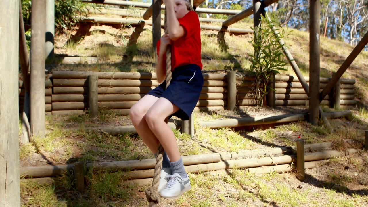 niña decidida a escalar la cuerda durante una carrera de obstáculos