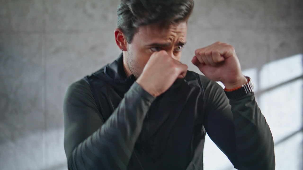 Powerful kickboxer fighting shadow in building closeup. Fighter practicing kicks