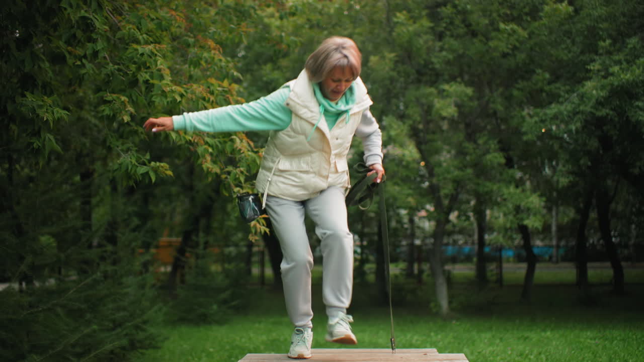 Dog trainer passing first obstacle with aspin dog during training session dog falls back while trainer moves toward second obstacle looking back to check dog surrounded by lush green park