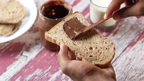 spreading chocolate spread on bread with milk