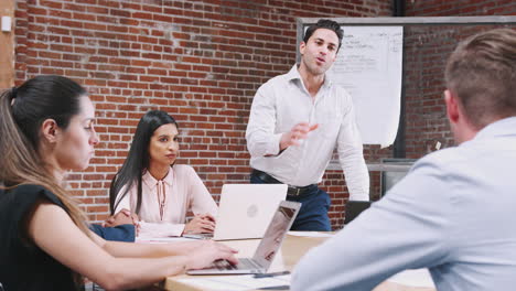 Mature-Businessman-Standing-And-Leading-Office-Meeting-Around-Table