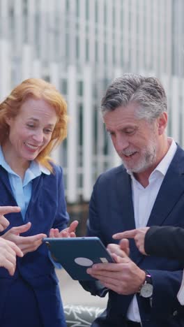 business professionals collaborating and discussing content on a digital tablet outdoors