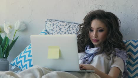 mujer trabajando en la computadora portátil en la cama