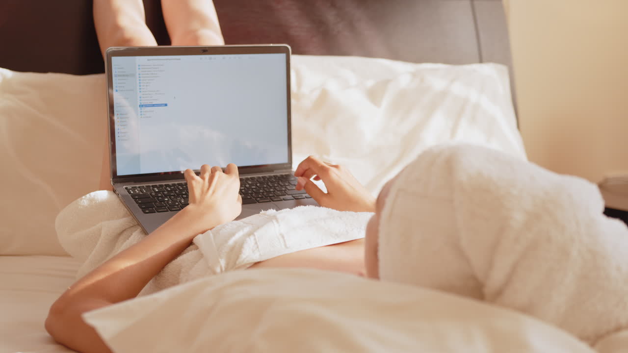 침대에 노트북으로 일하는 여자