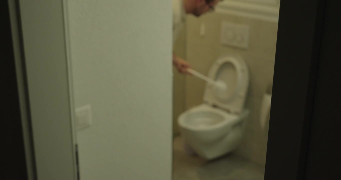 Person using a toilet brush to clean a toilet bowl in a residential bathroom. Concept of household cleaning, hygiene, sanitation, maintenance, and domestic chores.