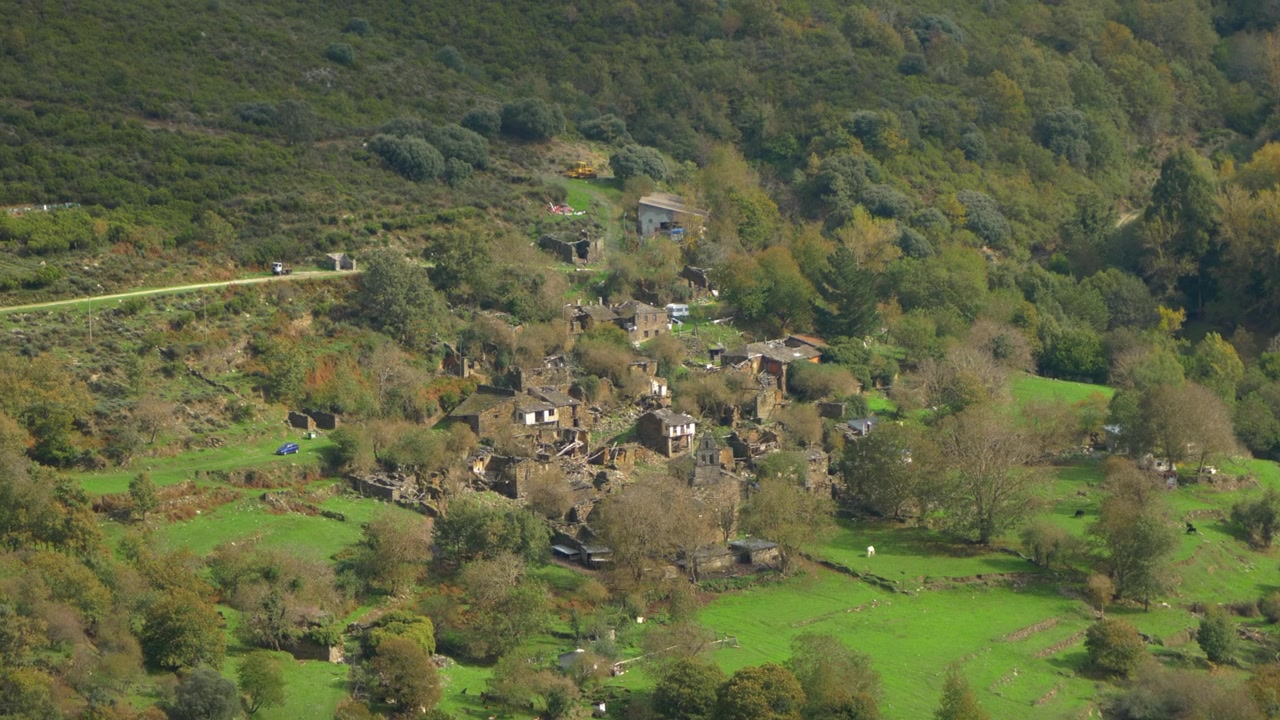 Aerial view over Santoalla do Monte in Galicia, Spain, showing the small mountain settlement, green valley and stone houses surrounded by remote countryside