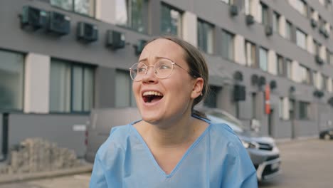 young female wearing scrub smiles and cheers outdoor