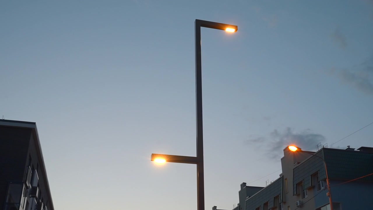 夕方から夜にかけてのシーケンスで、フレームの中央近くに高い街灯が映し出され、暖かい光が輝いている。