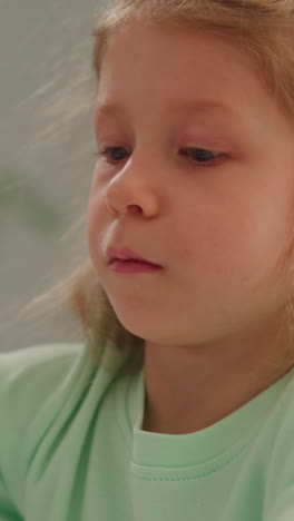 smart little girl shakes off paint tapping brush handle during ebru drawing lesson in light classroom closeup slow motion. development of creativity