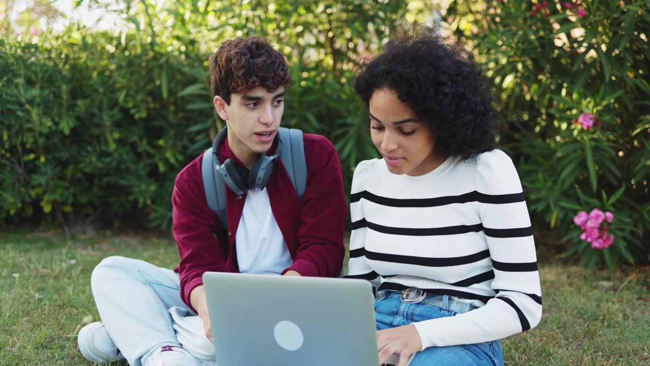Two Students Collaborating on a Laptop in a Park