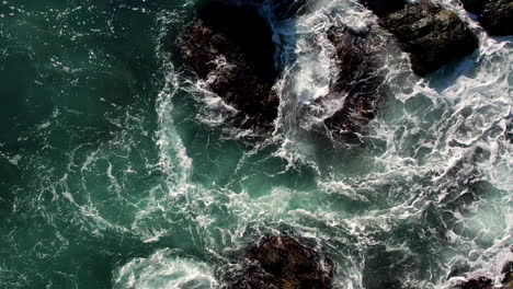 aerial view of waves crashing against rocky coastline