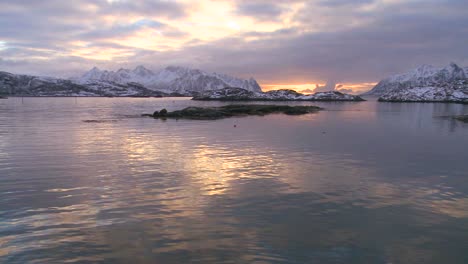 the midnight sun shines over a beautiful winter scene in north of the arctic circle in lofoten islands norway