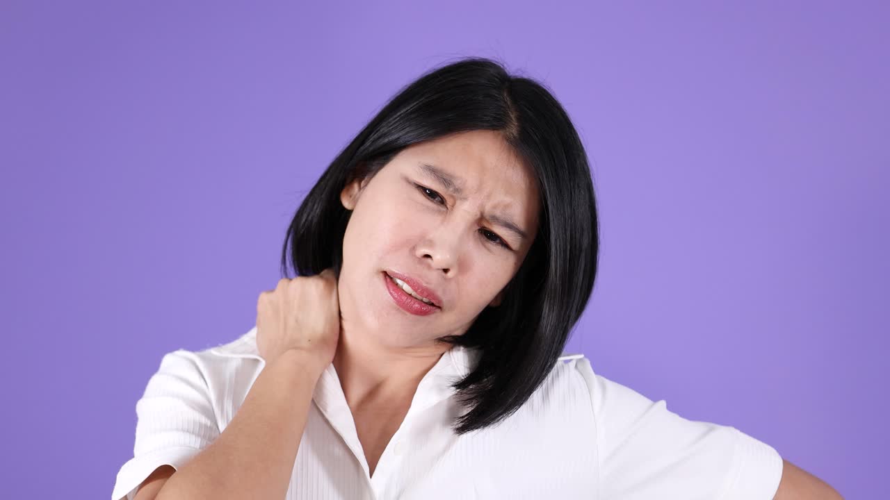 Woman in white shirt shows neck pain and fatigue, medium shot, neutral light, purple background