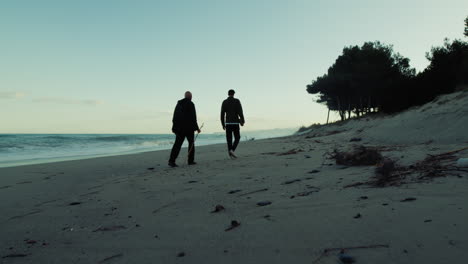 silhouette of anonymous people walking towards beach with stormy ocean waves