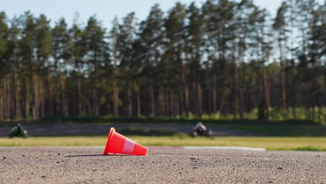 traffic cone on the road with motorcycles racing in background