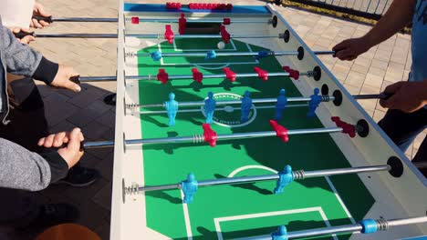 amigos jugando al futbolín afuera en un día soleado