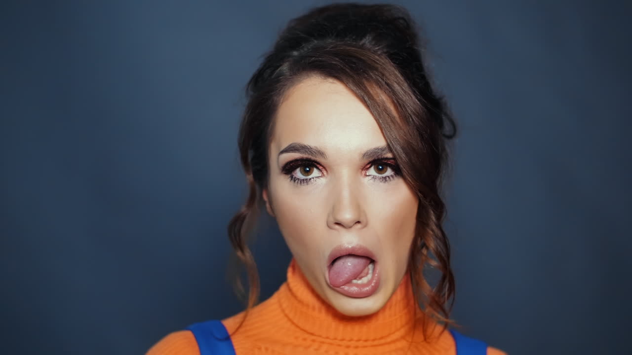 Young woman with beautiful appearance showing tongue. Girl showing grimaces