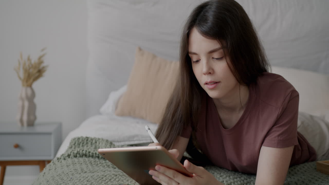 mujer dibujando en una tableta en la cama