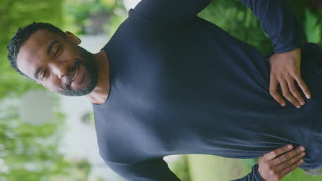 Retrato-En-Vídeo-Vertical-De-Un-Hombre-Sonriente-Y-Relajado-Parado-En-El-Jardín-De-Su-Casa-Después-De-La-Jubilación