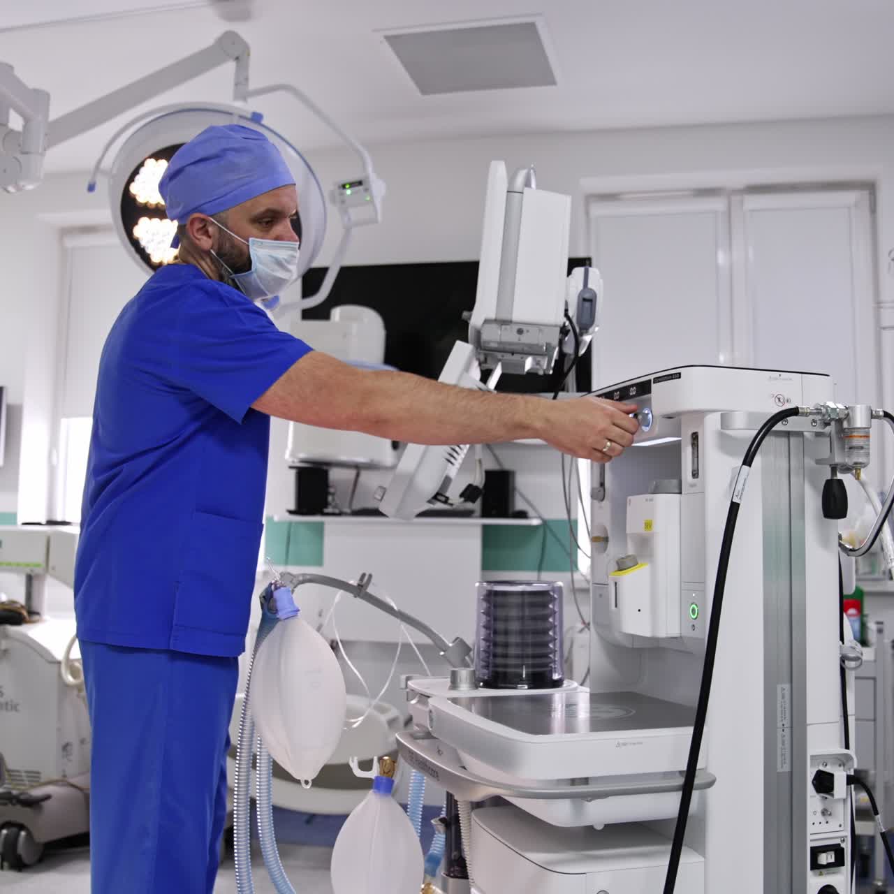 Anesthesiologist standing near the lung ventilator machine. Doctor switching on equipment in surgery room