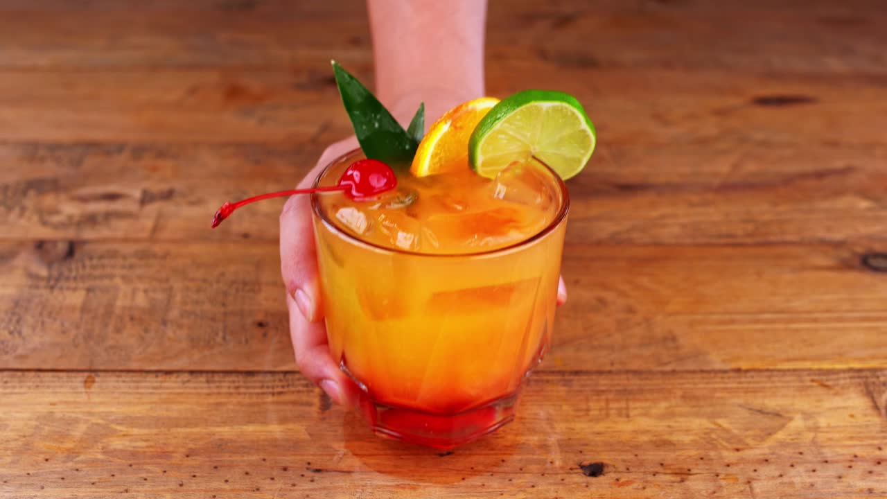 cerca de un cóctel de mezcal siendo retirado de una mesa de madera en un restaurante