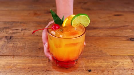 Close-up-of-a-mezcal-cocktail-being-removed-from-a-wooden-table-in-a-restaurant