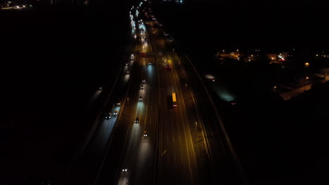 aerial view looking down over busy night time highway traffic vehicles with illuminated headlights travelling to destination