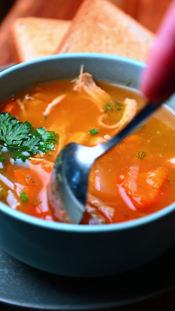 Hjertevarmende suppe med strimlet kylling. Klar suppe fyldt med stykker af strimlet kylling, grøntsager og friske urter